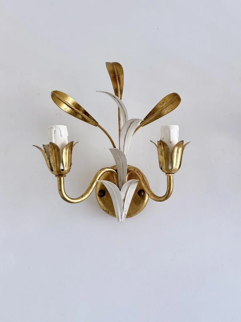 Front view of a 1970s Italian two-light tole wall sconce attributed to Masca, finished in aged gold and ivory white.