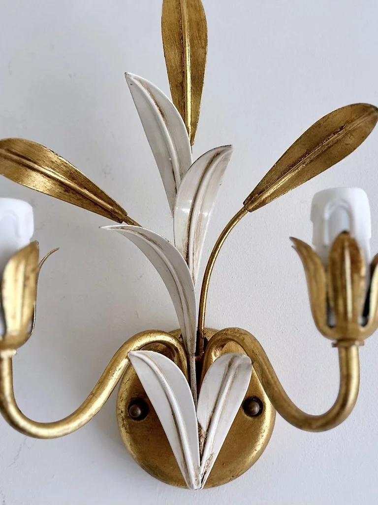 Close-up of the original aged-gold finish and vintage patina on the botanical leaves and curved arms of the Italian sconces.