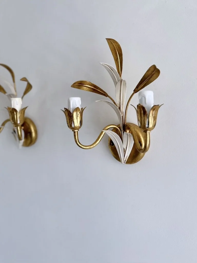 Pair of Hollywood Regency wall sconces with symmetrical two-arm designs and hand-formed gold and white metal leaves.