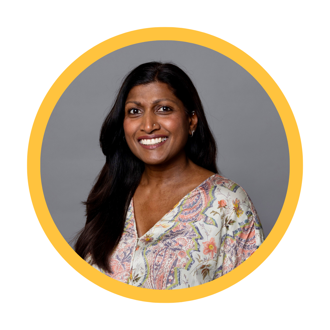 Indian woman smiling long brown hair wearing a floral blouse.