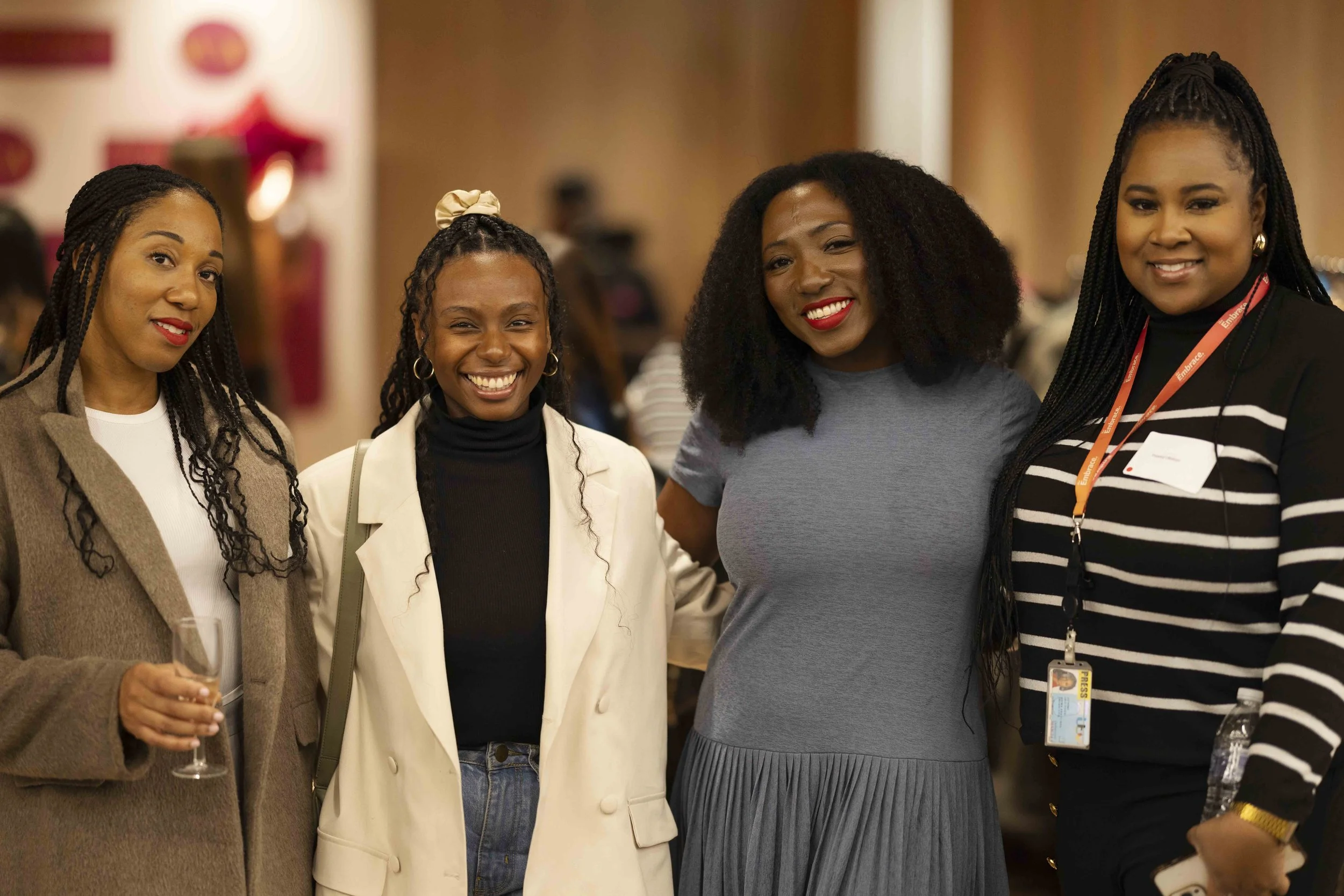 Four women standing together at an event, smiling and posing for the photo.