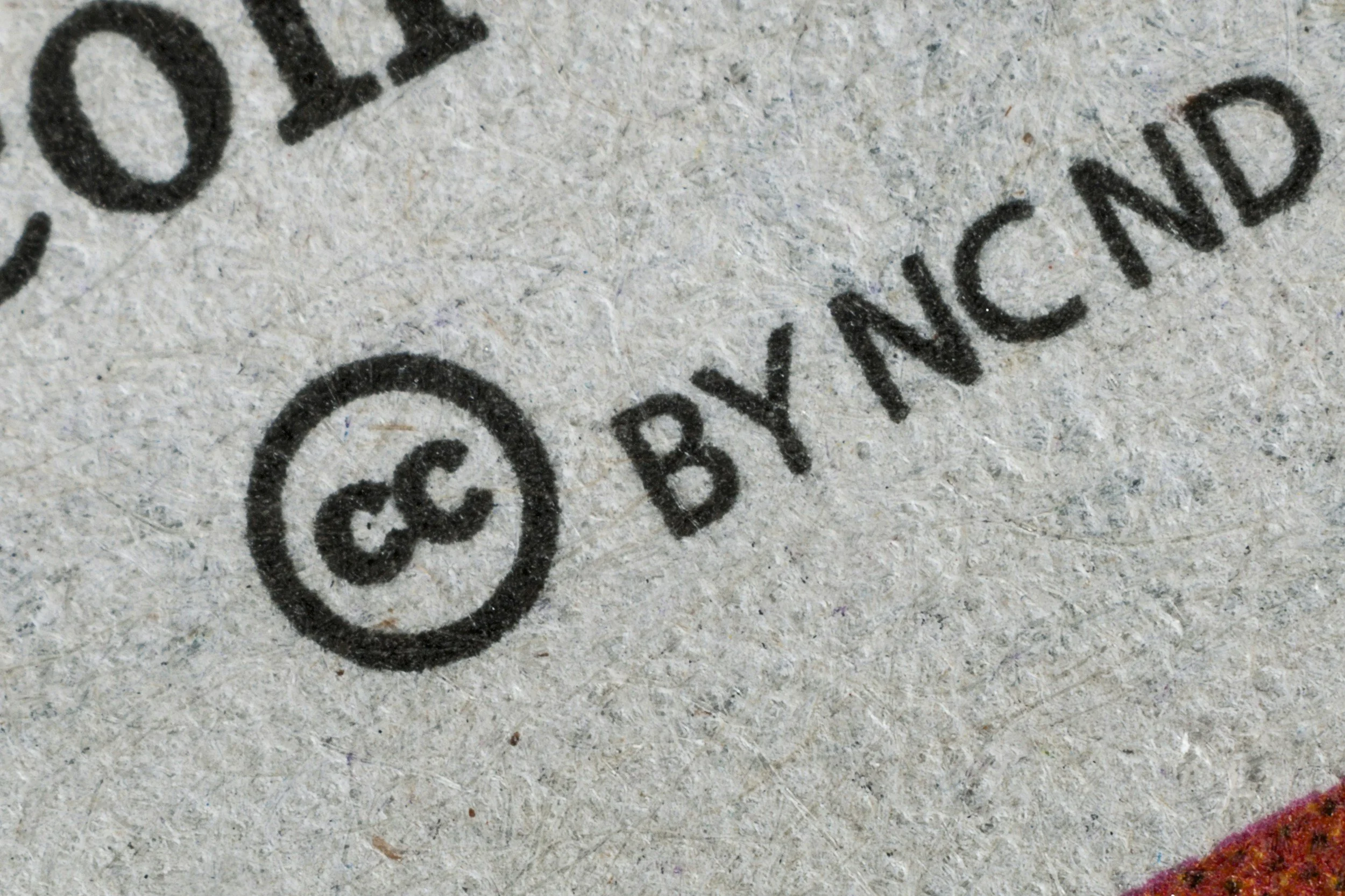 Close-up of a recycled paper surface with printed text 'BY NCD' and an encircled recycling symbol.