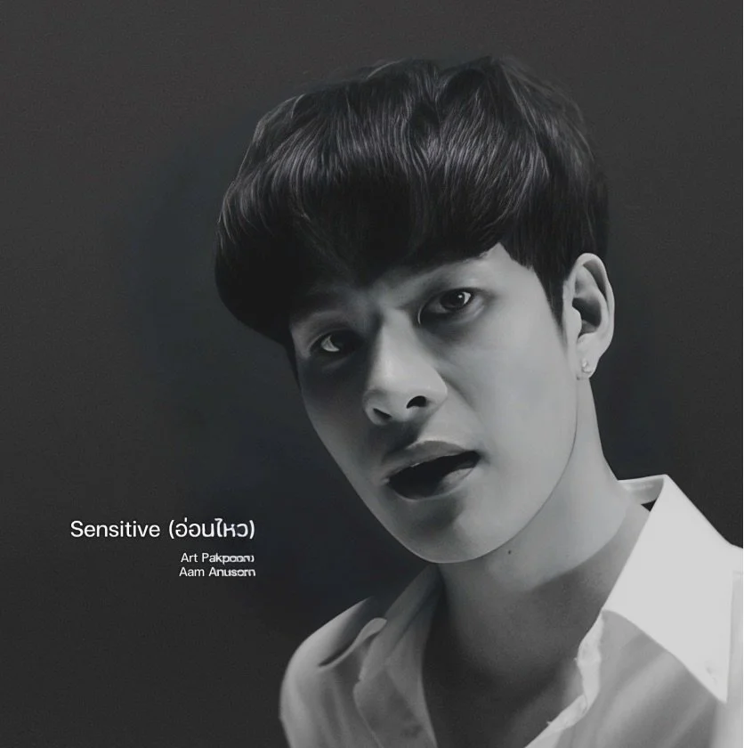 Black and white portrait of a young man with dark hair, wearing a white shirt, looking directly at the camera with a neutral expression.