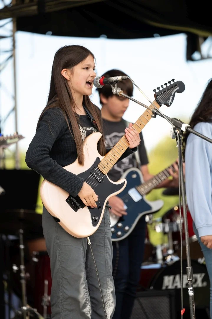 A teenage girl playing guitar on stage