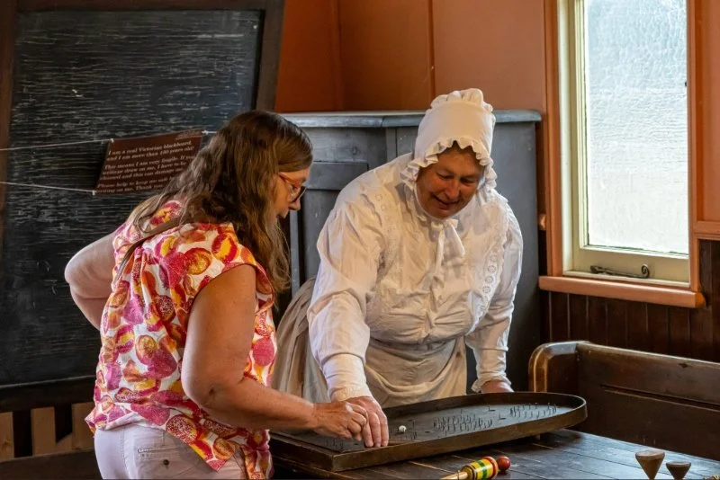 lady in victorian costume explaining a game to a female visitor