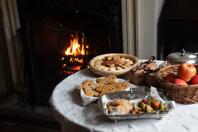 Christmas table laid with gingerbread, biscuits, apples and wrapped gifts