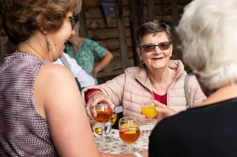 A smiling lady is being offered a glass of Pimms while standing in a historic barn
