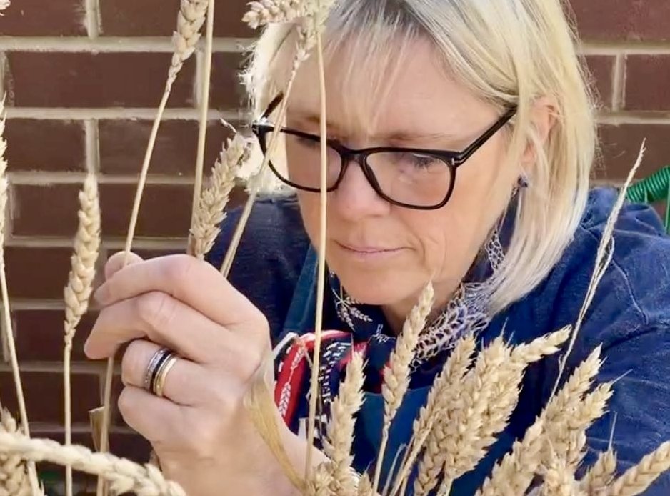 A lady shows how to plait using straw