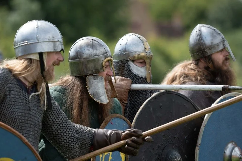 A line of men dressed as Viking warriors with helmets, axes and sheilds
