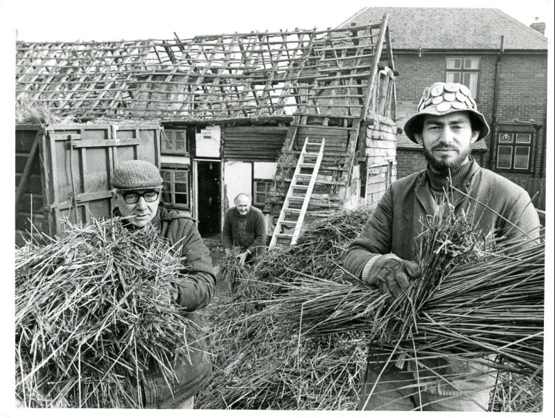 Two men holding thatching straw