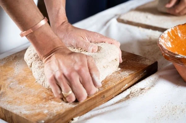 Hands kneading bread dough on a wooden board