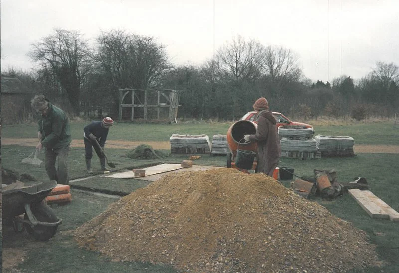 Men digging a hole with cement mixers nearby