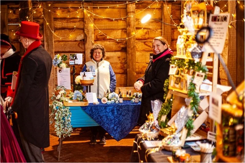 Local artisan craft stalls inside a historic barn decorated with Christmas lights