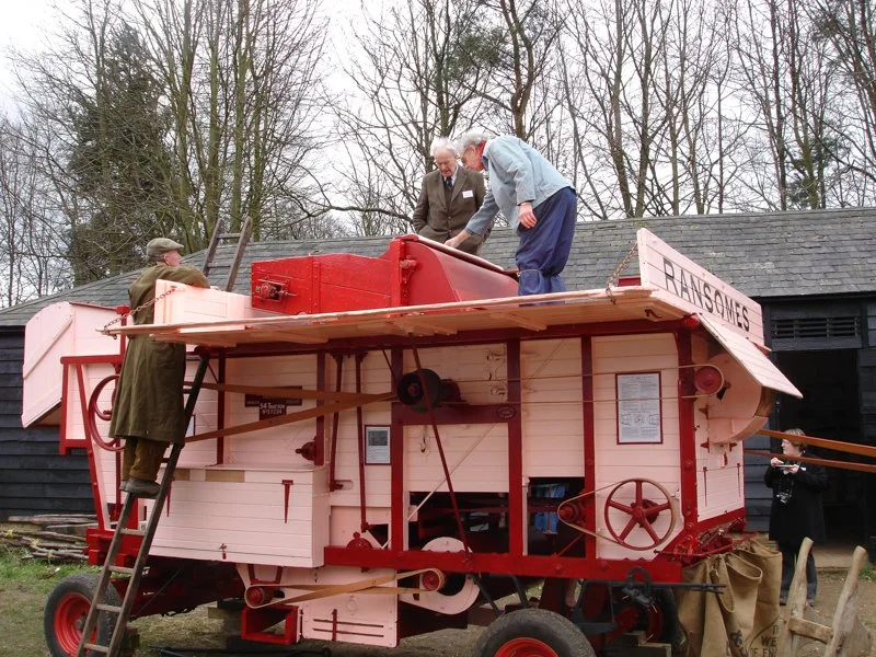 men working on to of farming machinery 