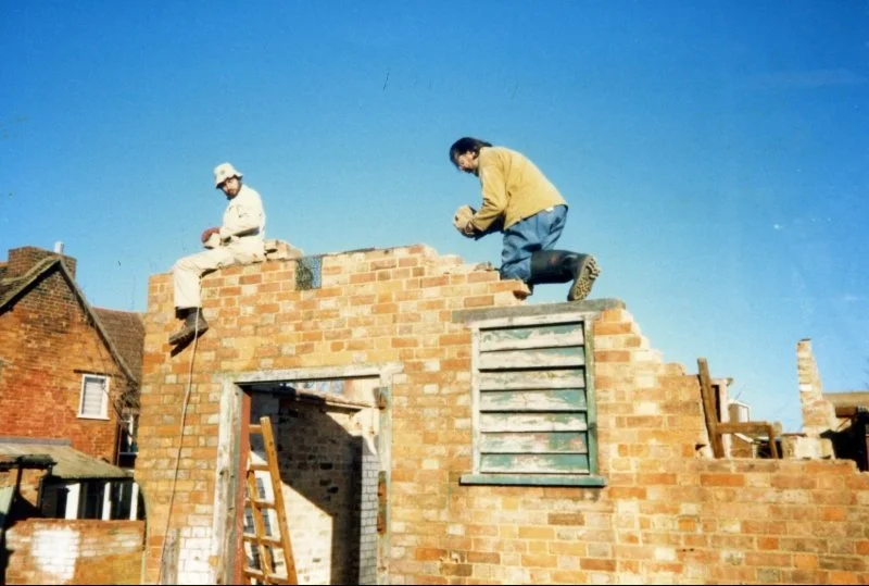 Men sat on top of building dismantling bricks