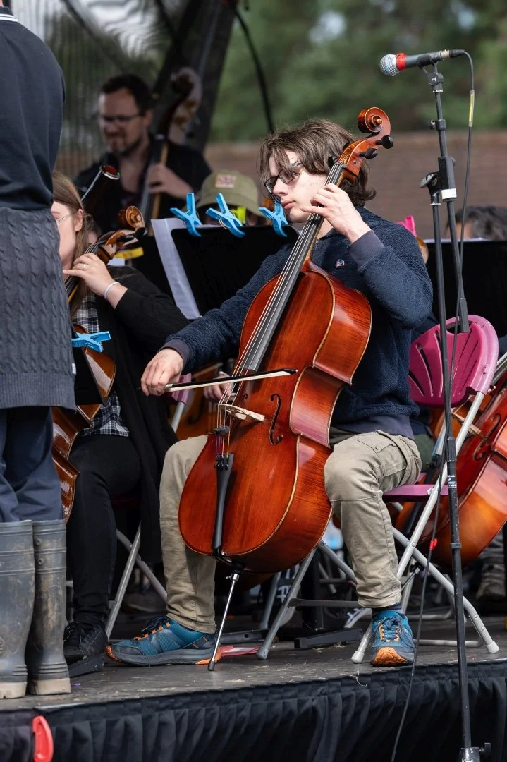 A young man playing cello on stage