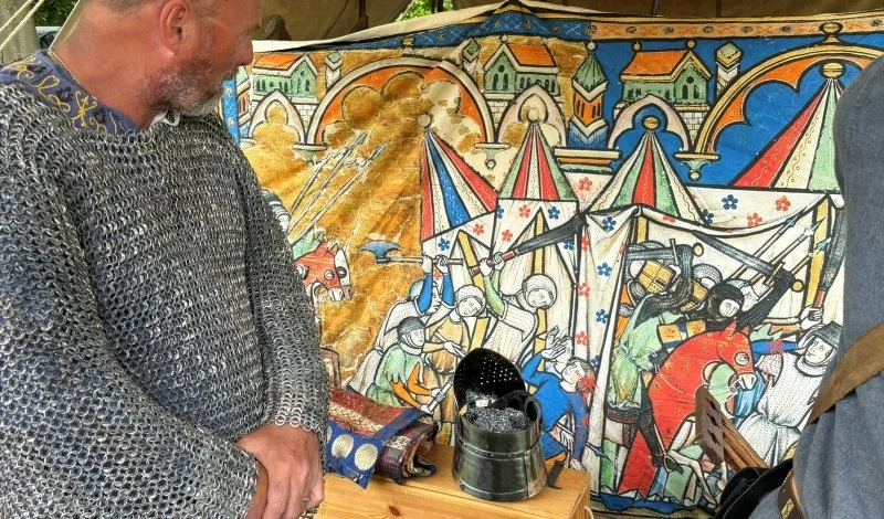 A re-enactor standing next to a medieval style tapestry