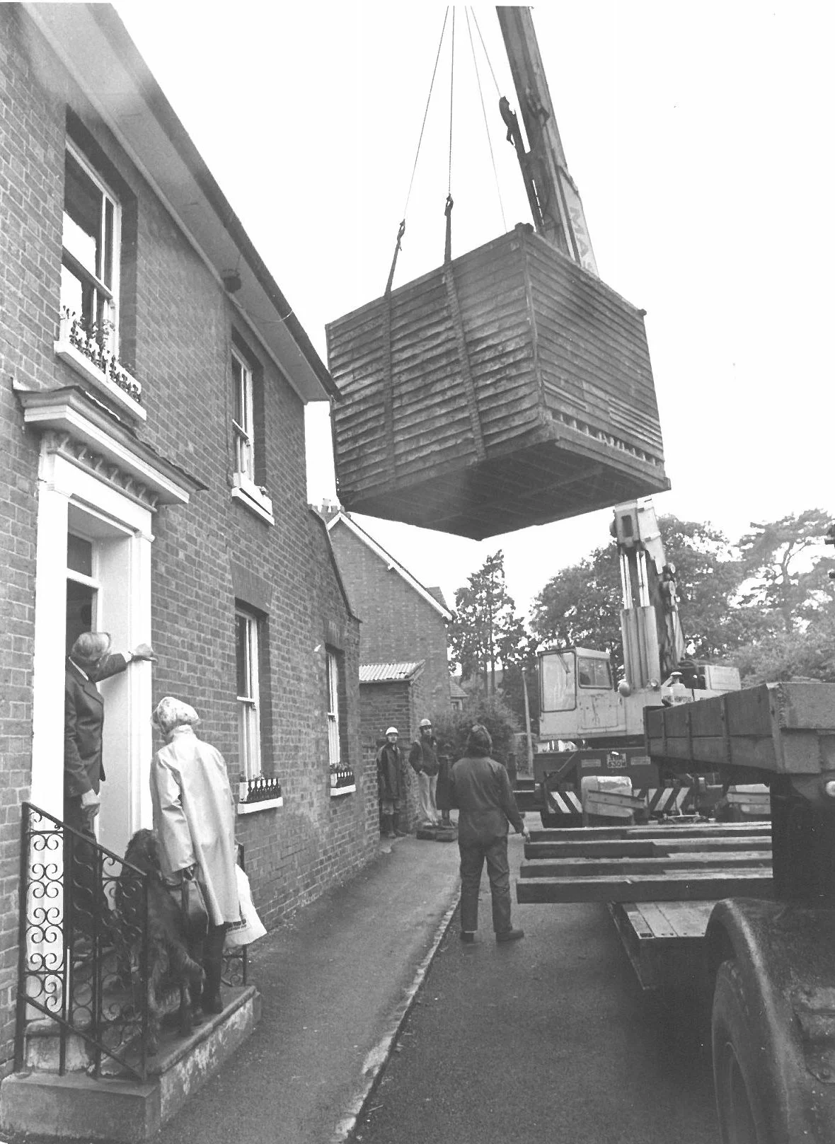 Granary being carried over a house by a  crane