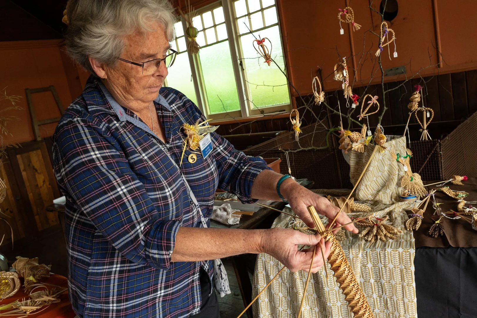 A lady shows how to plait using straw