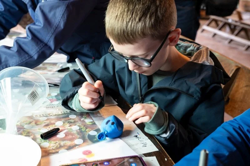A boy doing a craft activity colouring eyes onto a balloon