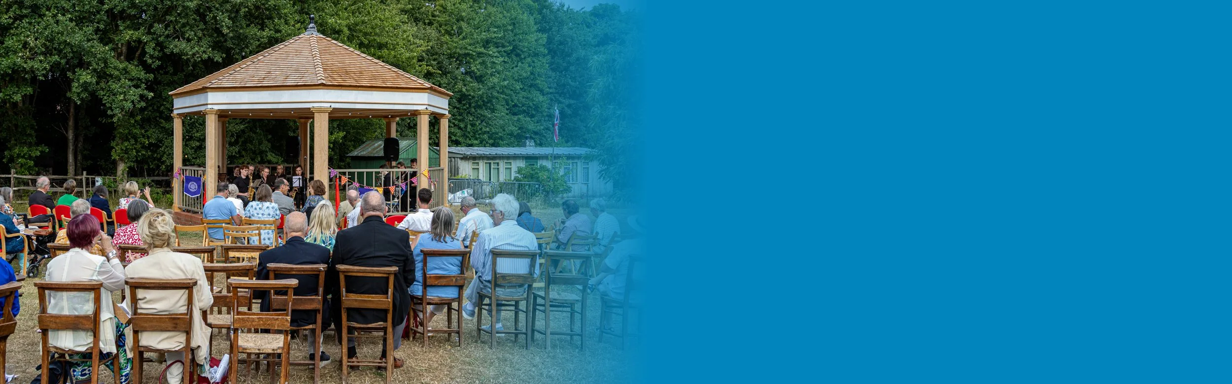 A traditional bandstand with people sitting watching a concert