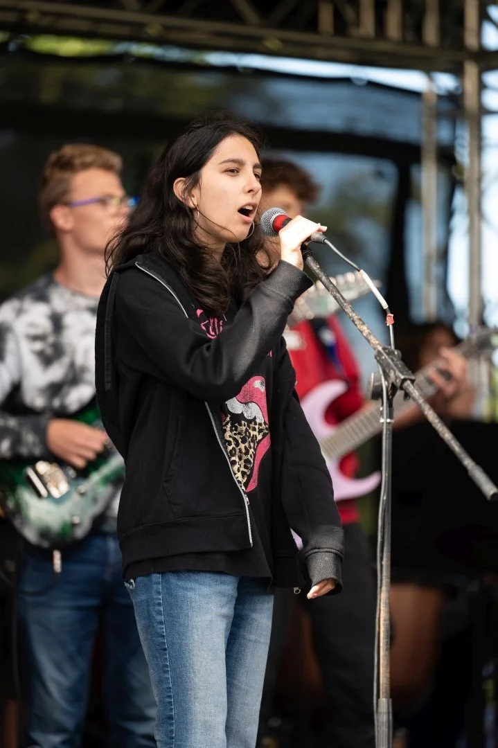 A teenage girl signs into a microphone on stage