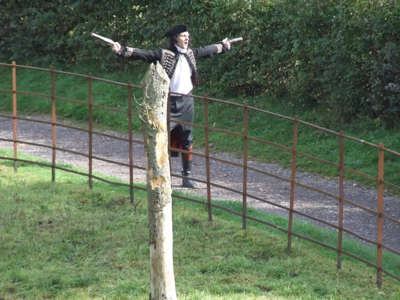 man walking down path dressed as a highwayman with arms outstretched