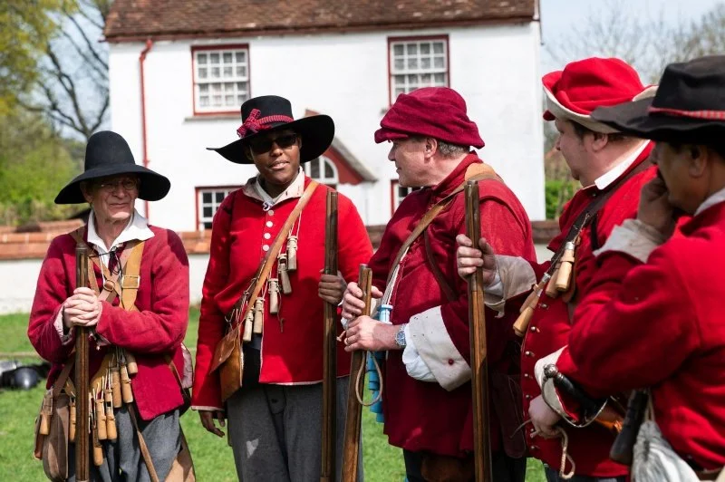 A group of English Civil War reenactors outside a white cottage at Chiltern Open Air Museum
