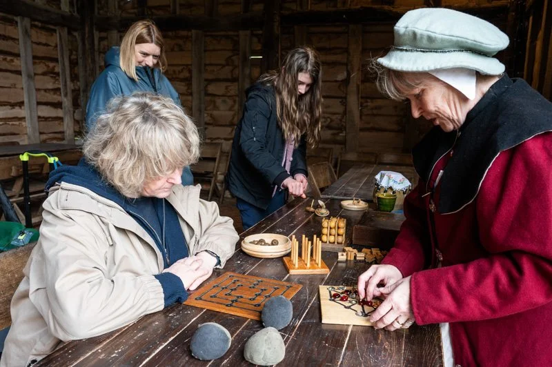 woman playing old board game with tudor reenactor stood infront