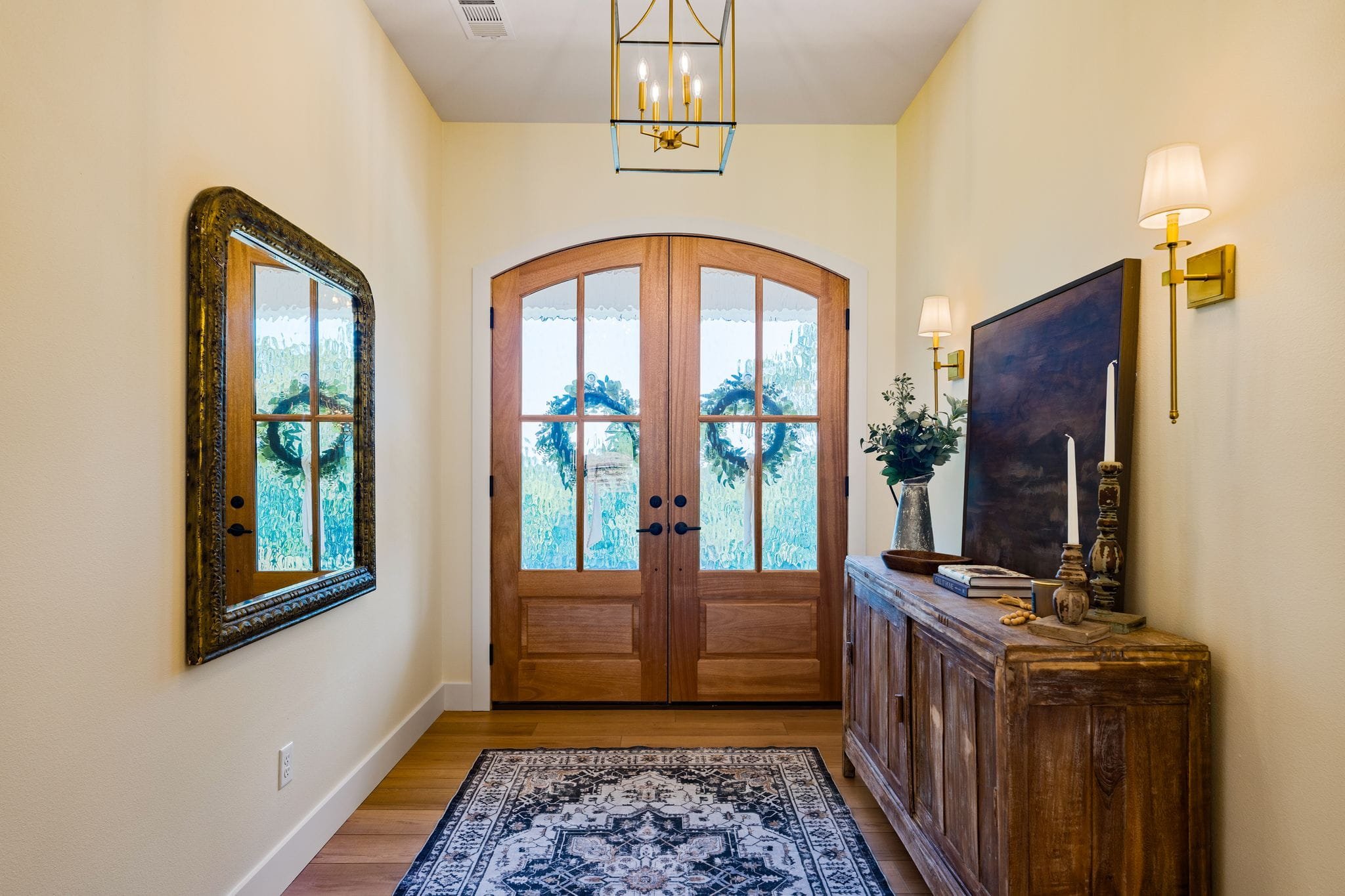 Warm farmhouse entryway with double wood front doors and rustic console table