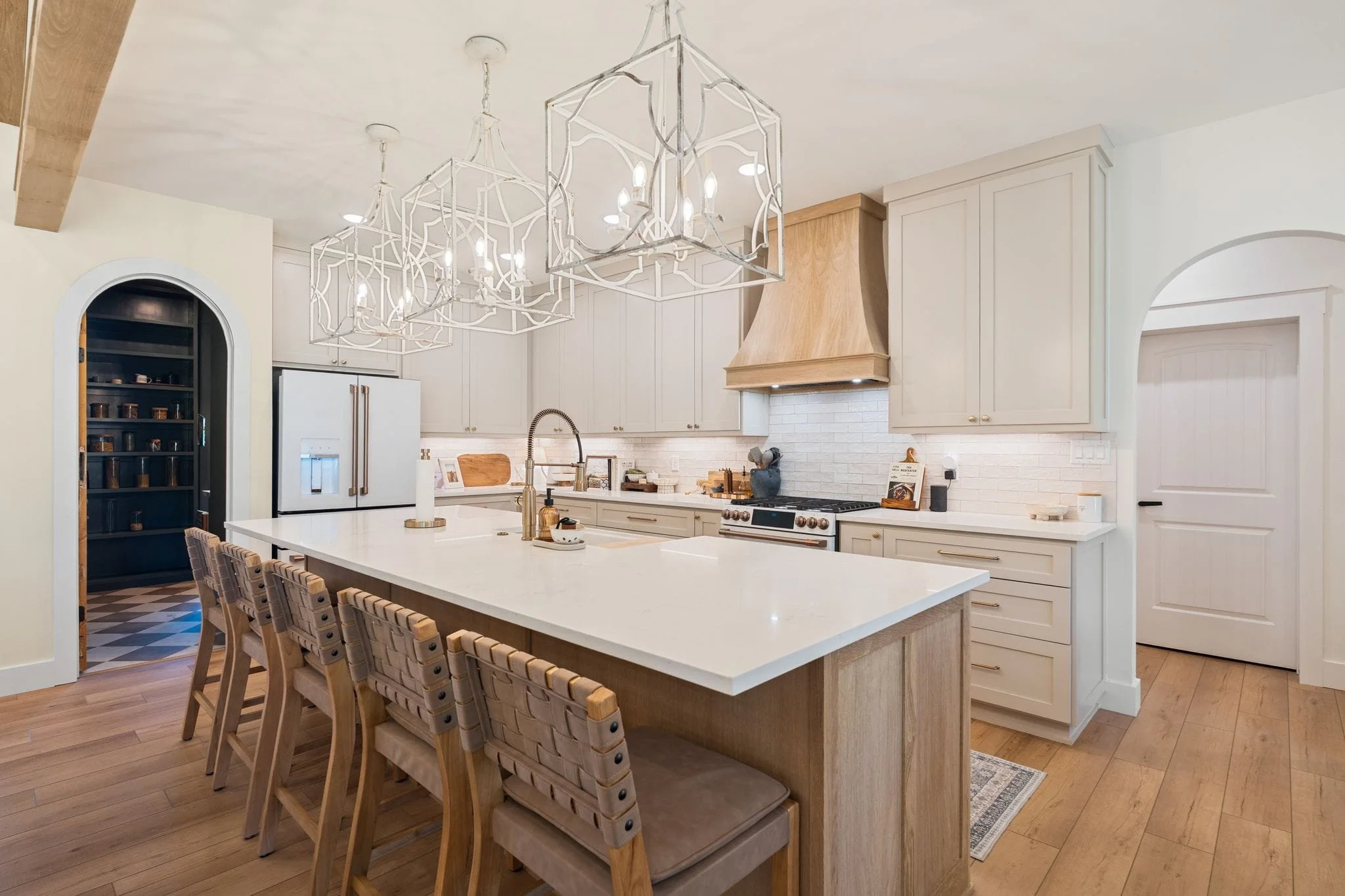 Modern kitchen with large island seating, custom cabinetry, white countertops, and decorative pendant lighting.