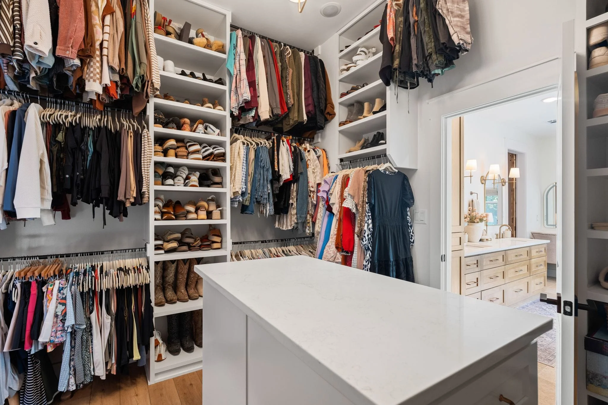 Custom primary closet featuring extensive shelving, clothing storage, shoe organization, and access to ensuite bathroom.
