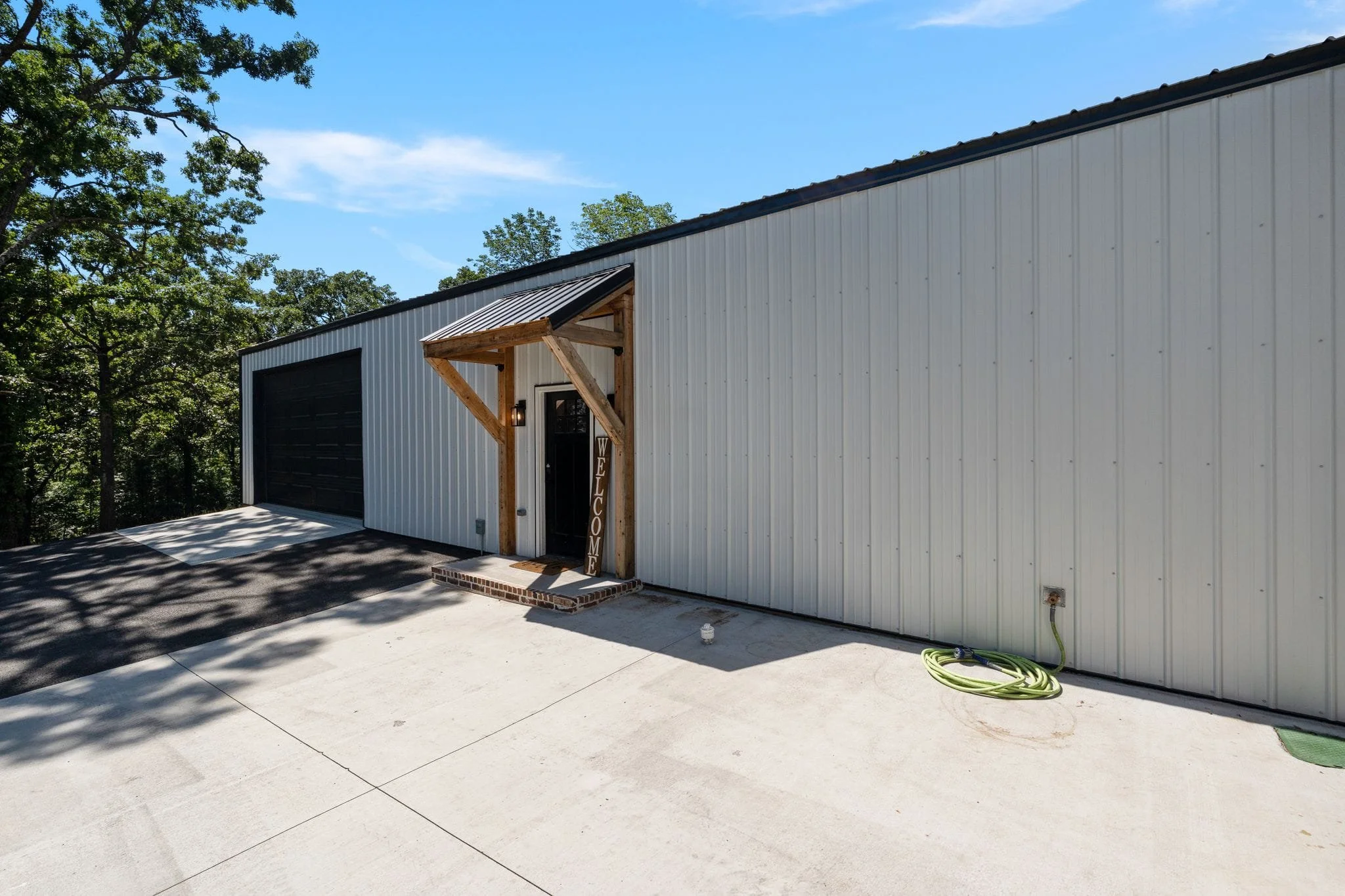 Detached workshop exterior with covered entry and black garage door