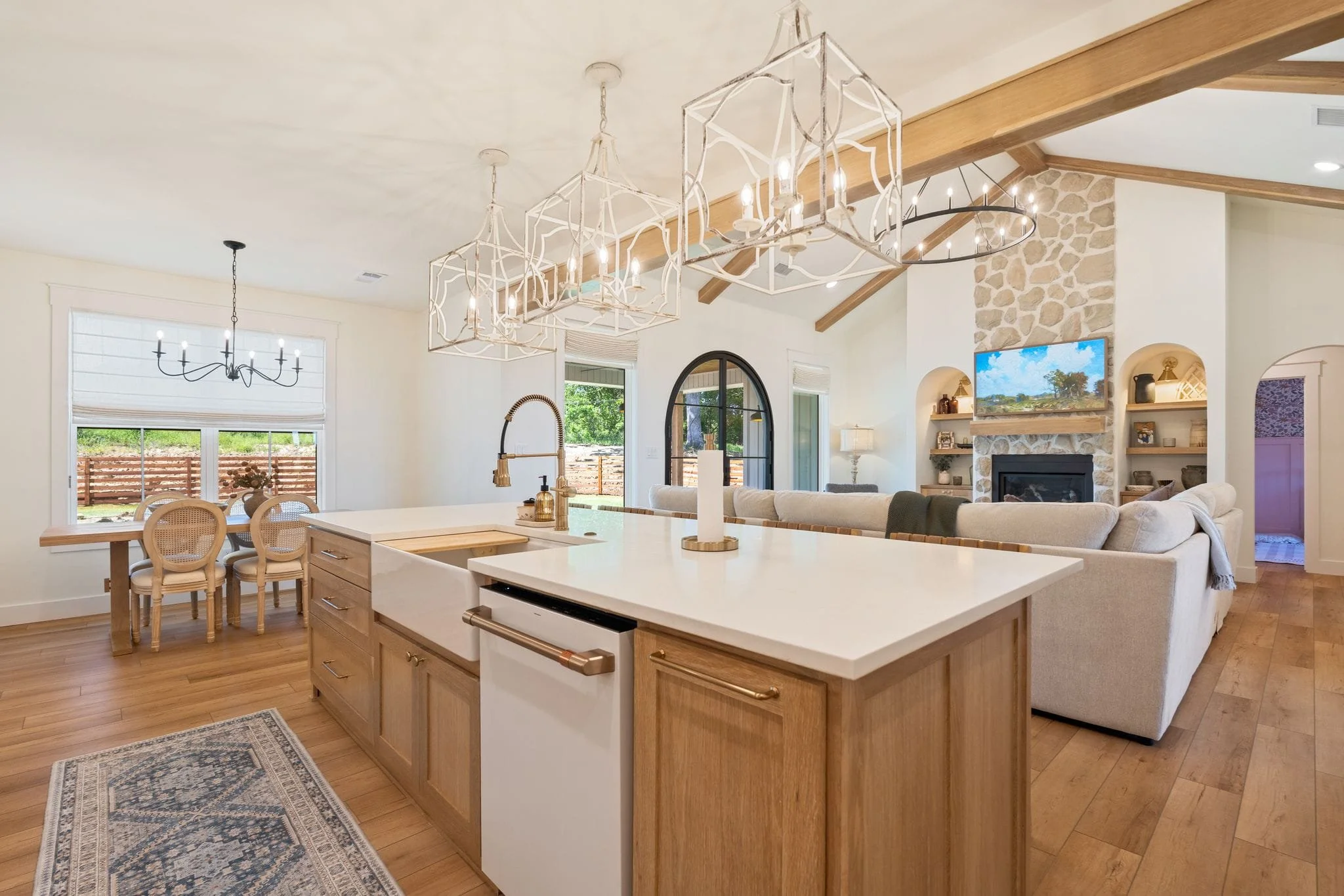 Open kitchen and dining area with wood island cabinetry, pendant lights, and views into the living room.