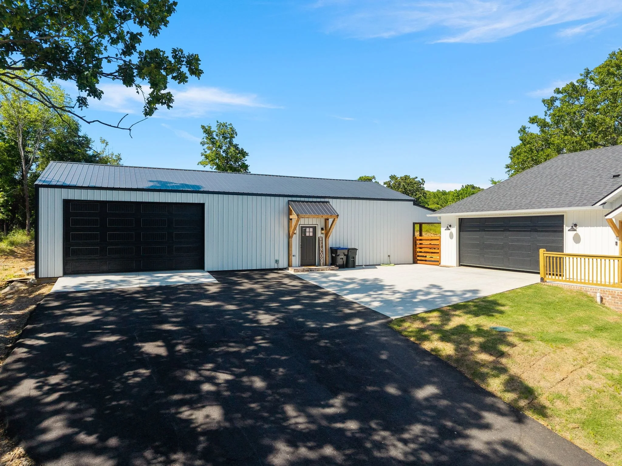 Detached metal shop building with black garage doors and concrete driveway
