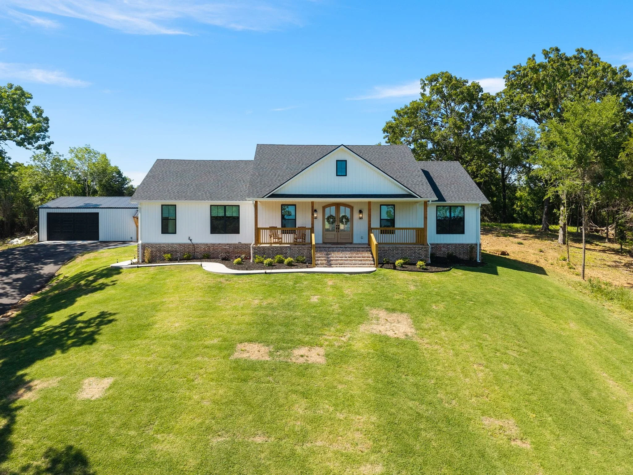Wide aerial view of custom farmhouse with detached shop building and landscaped yard