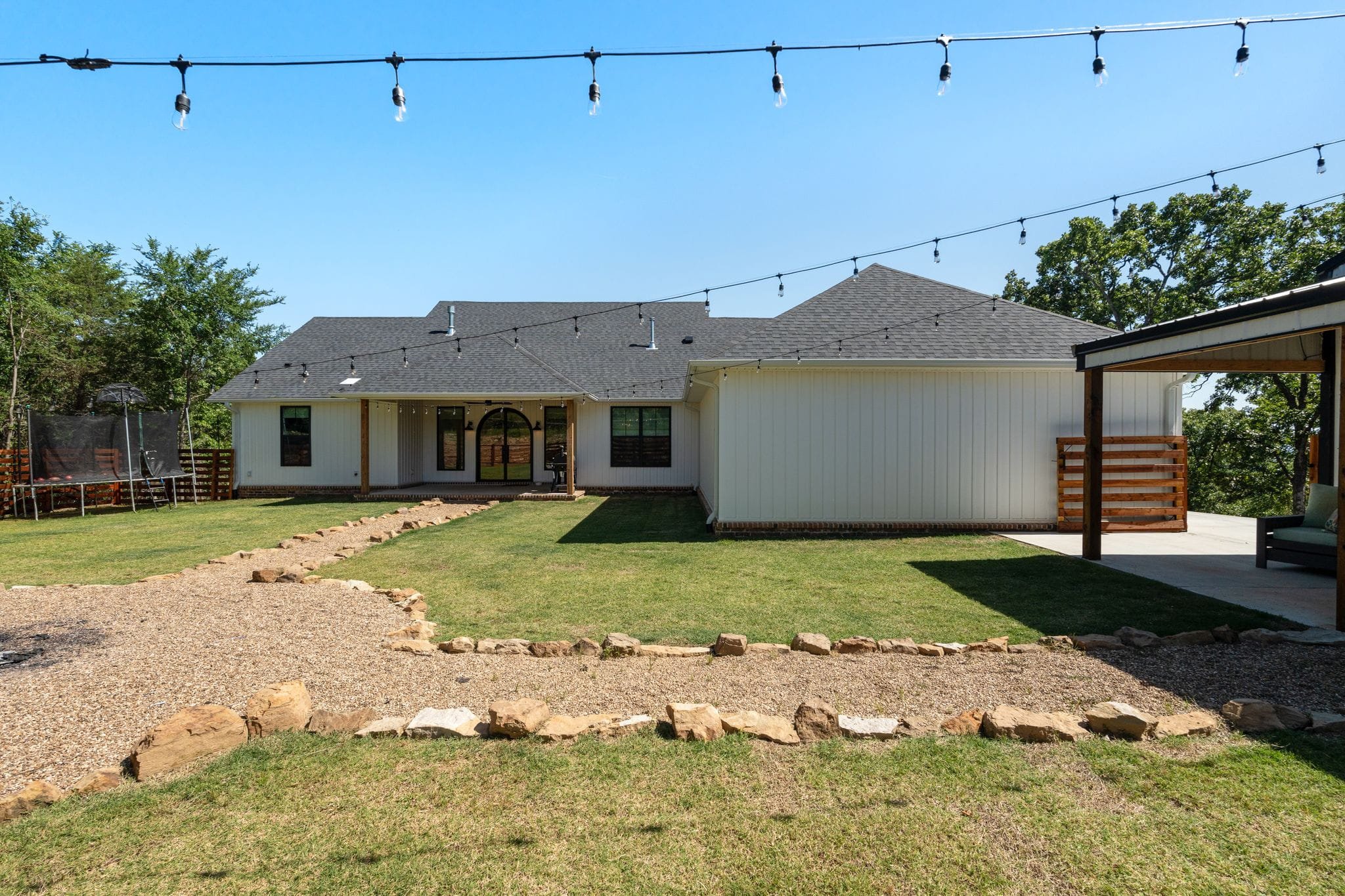 Rear exterior of white farmhouse with covered patio and landscaped fire pit