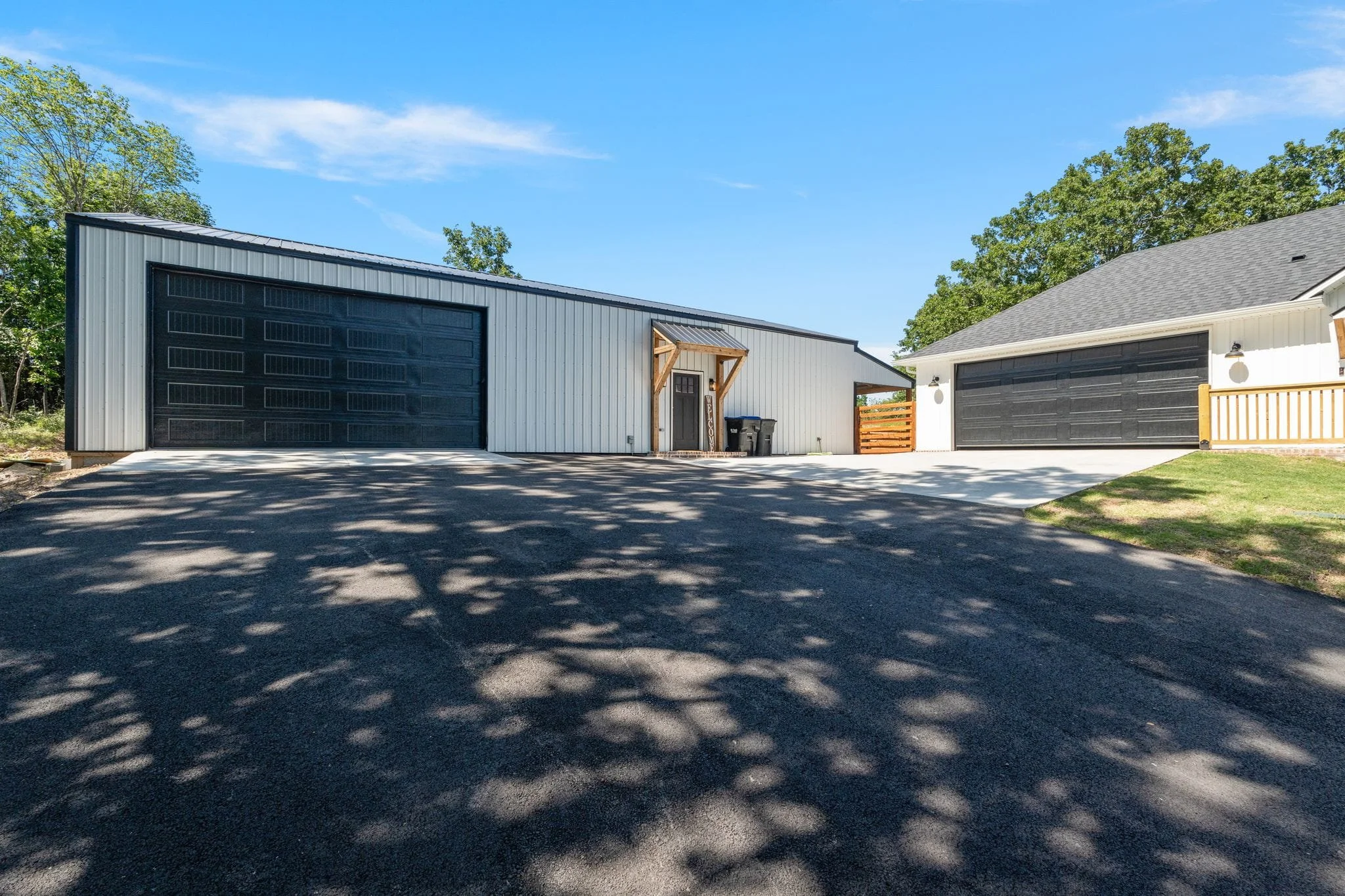 Large detached shop building with oversized black garage doors and concrete driveway