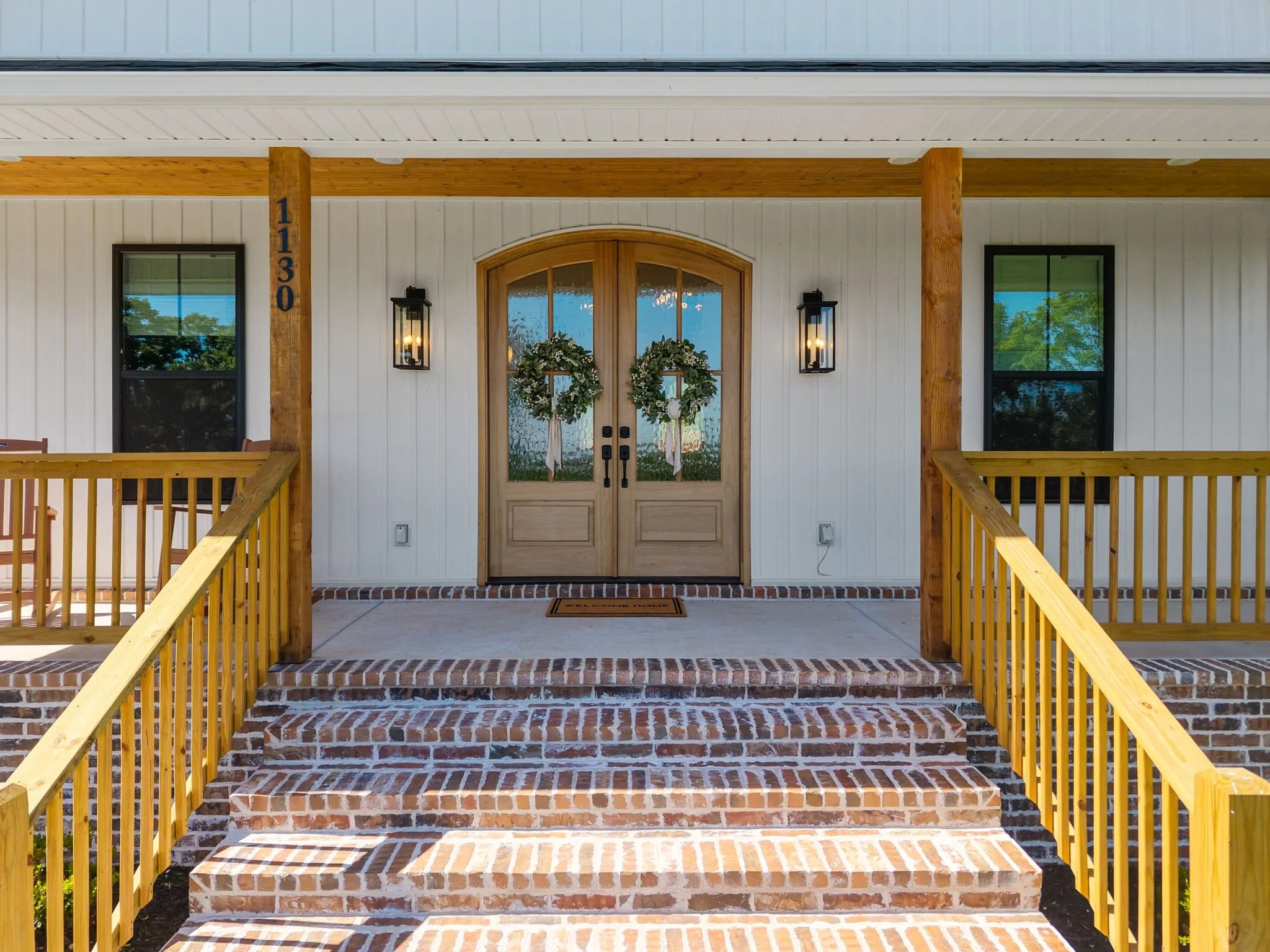 Brick front steps leading to arched double wood doors on covered porch