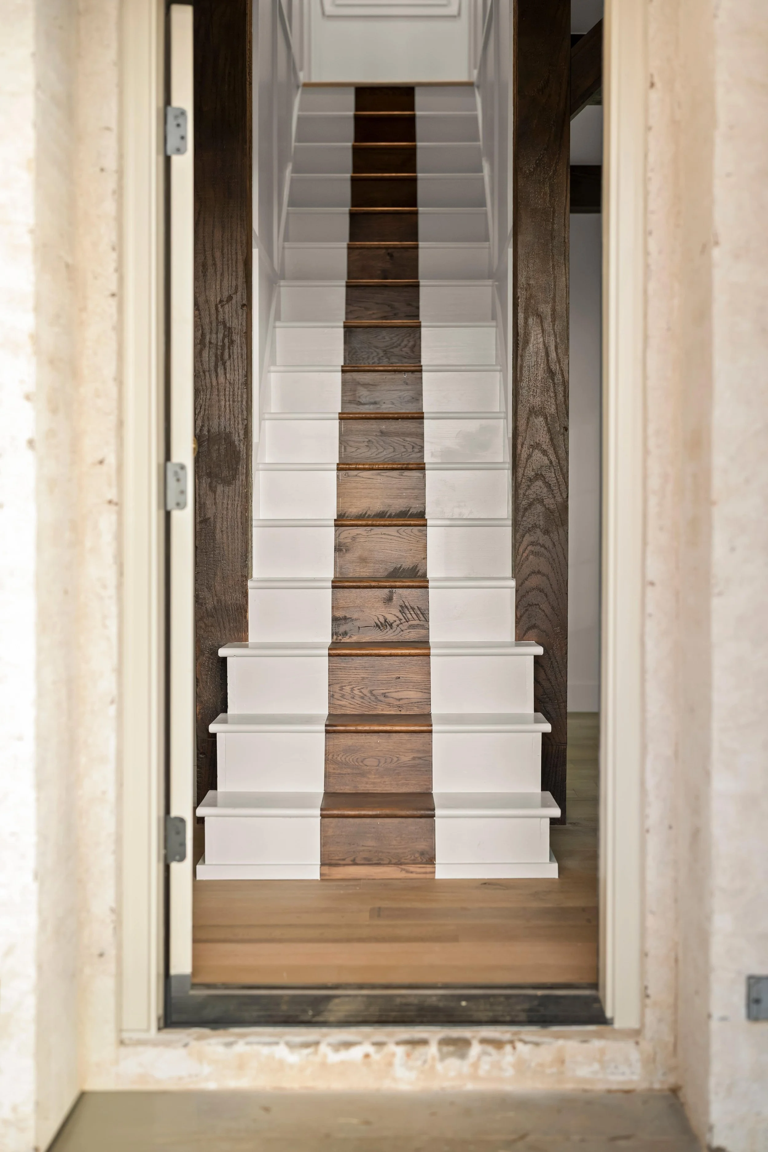 A staircase with white risers and dark wooden treads viewed through a doorway.