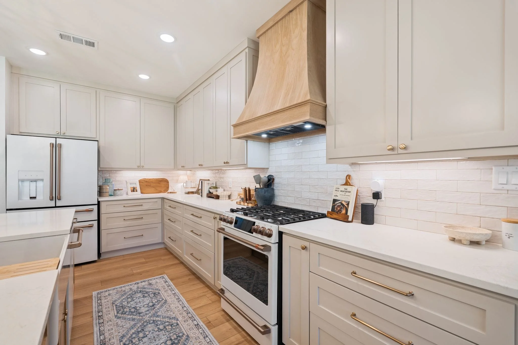 Bright kitchen with white subway tile backsplash, custom cabinetry, gas stove, and oversized island sink.