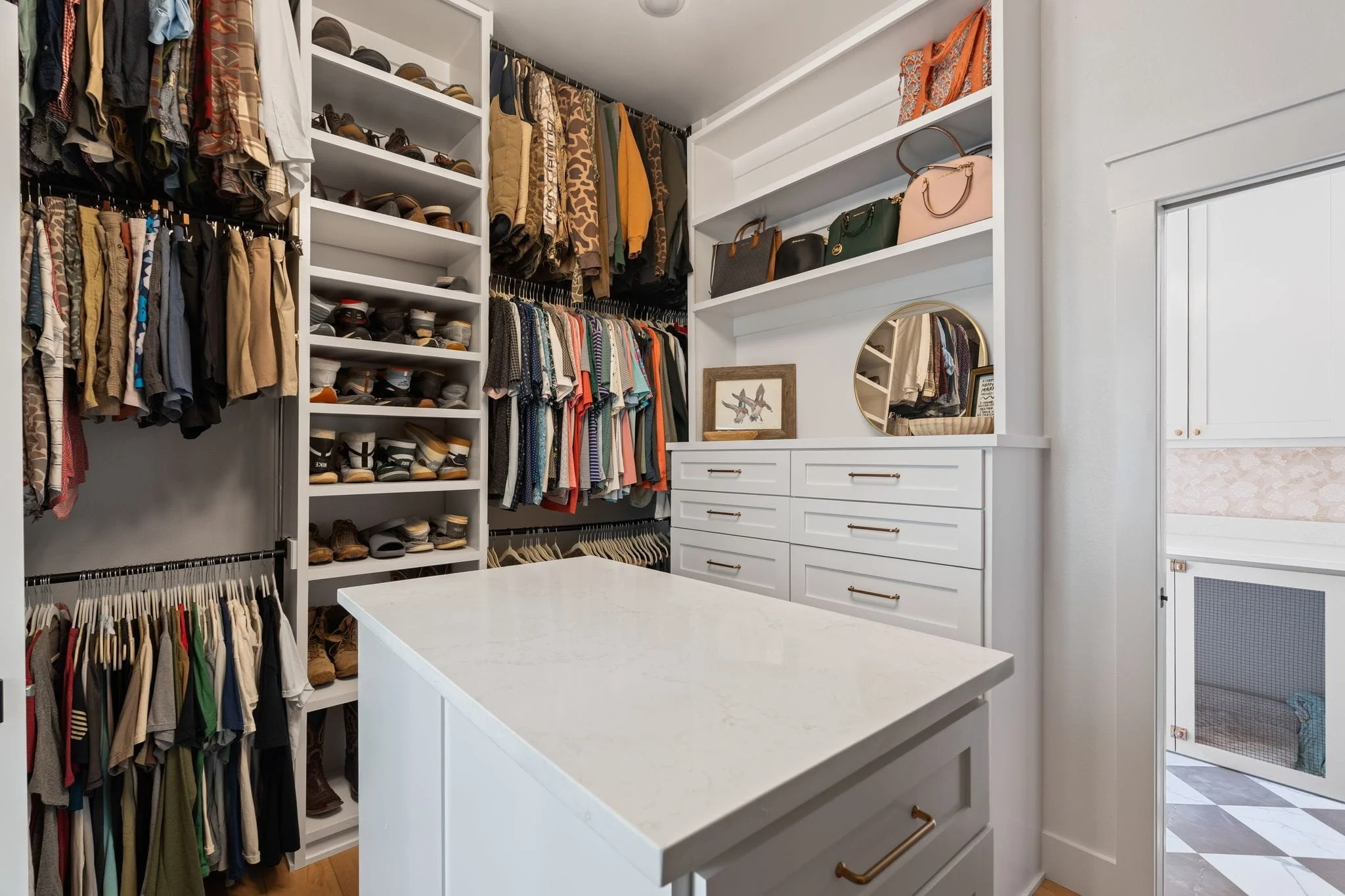 Spacious walk-in closet with center island, custom shelving, hanging storage, and built-in drawers.