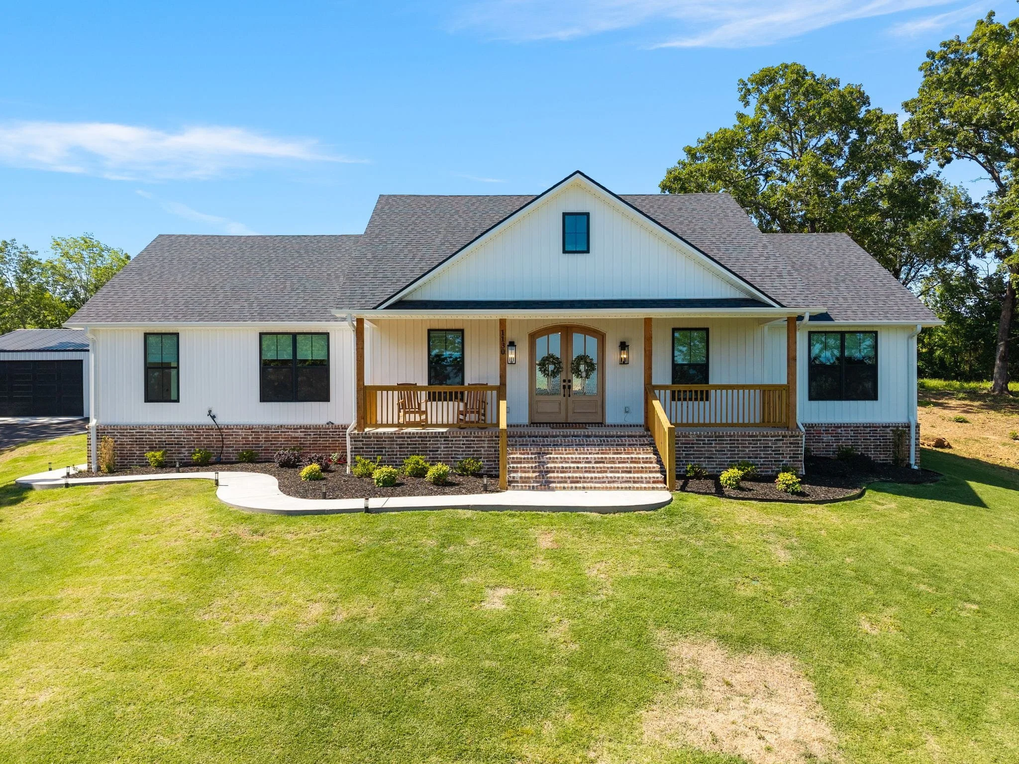 Front view of custom white farmhouse with covered front porch and brick steps