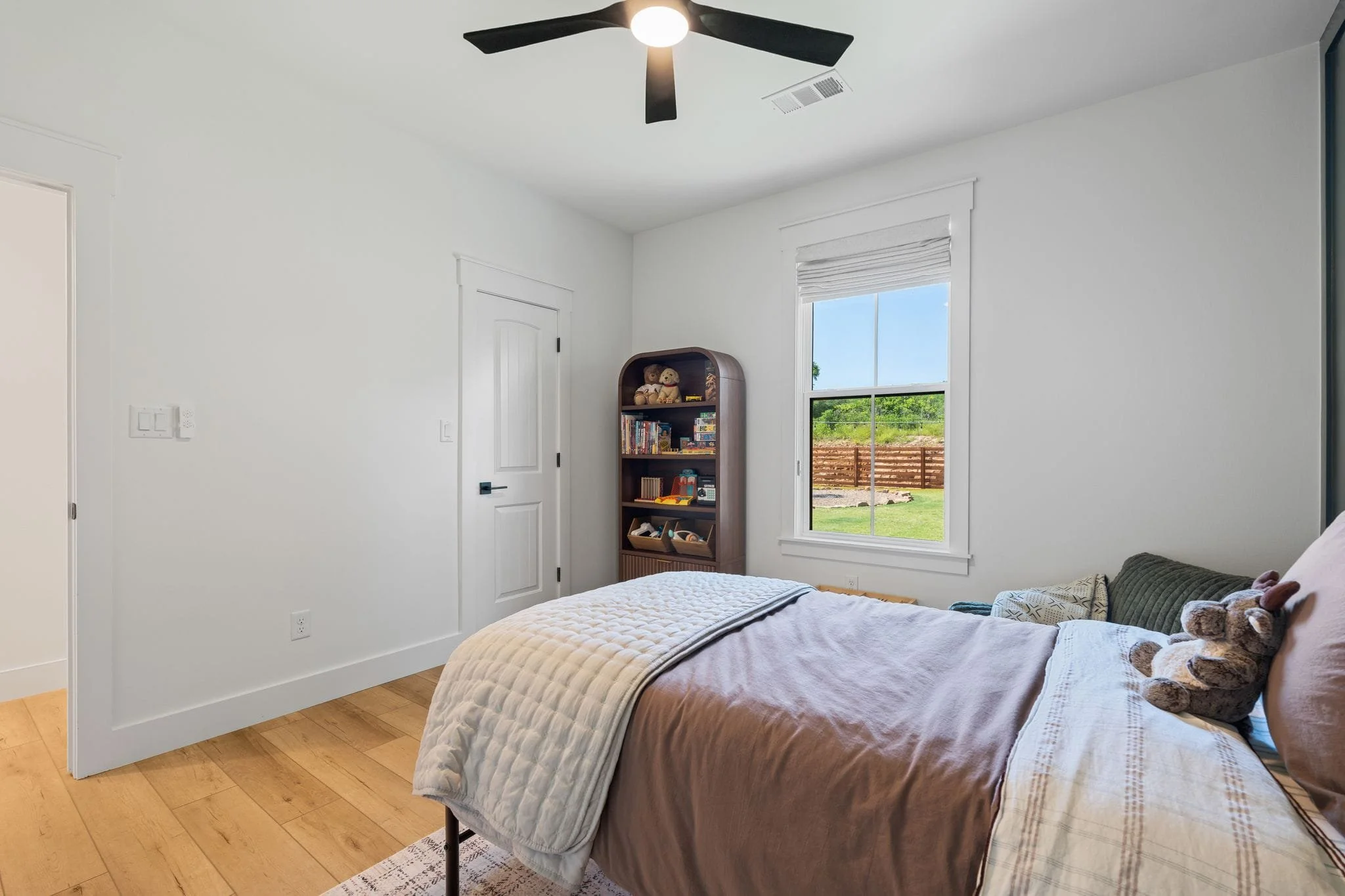Cozy bedroom with green paneled accent wall, plush bedding, large window, and neutral decor.