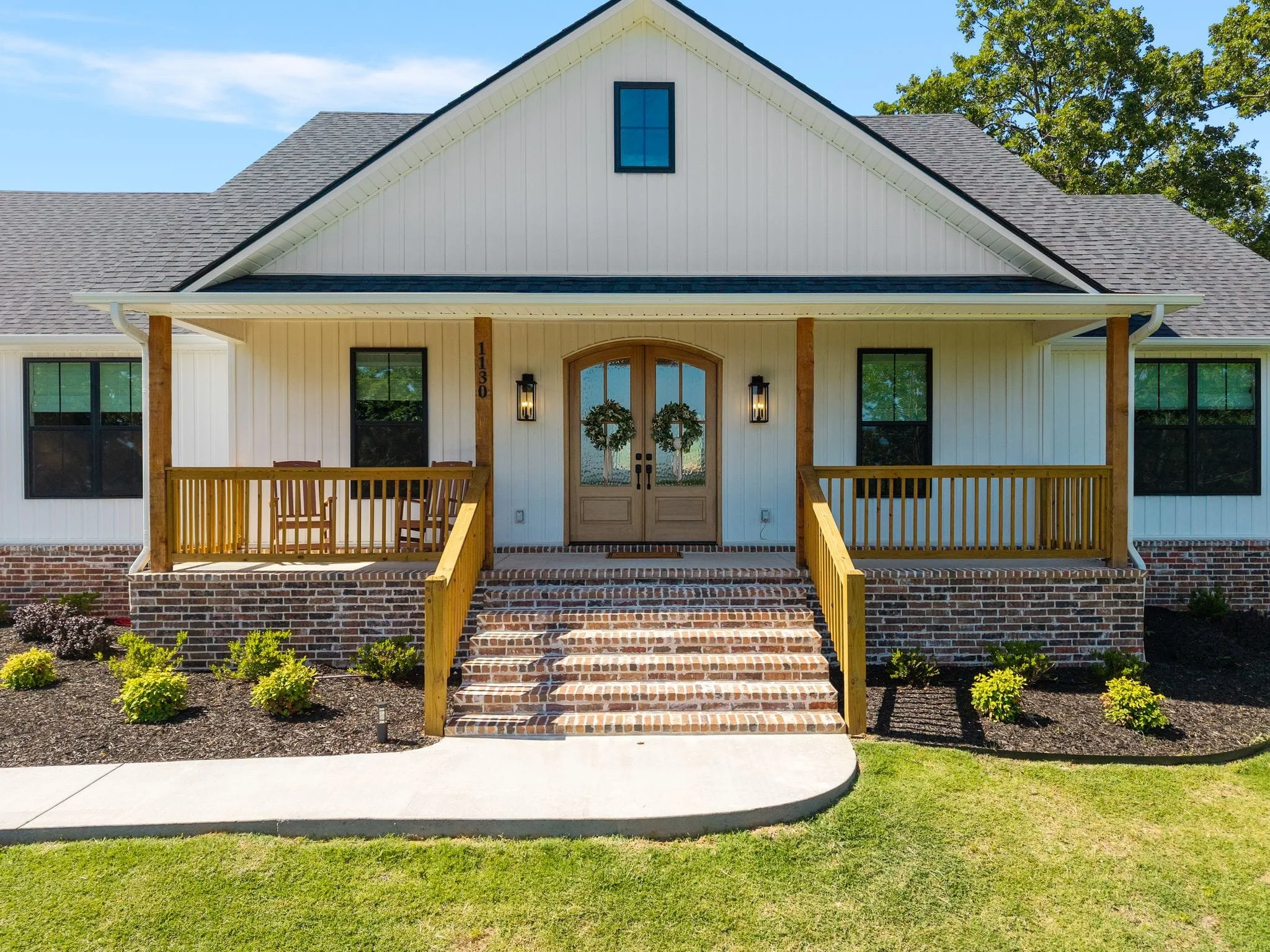 Close view of front porch with brick staircase and double wood entry doors