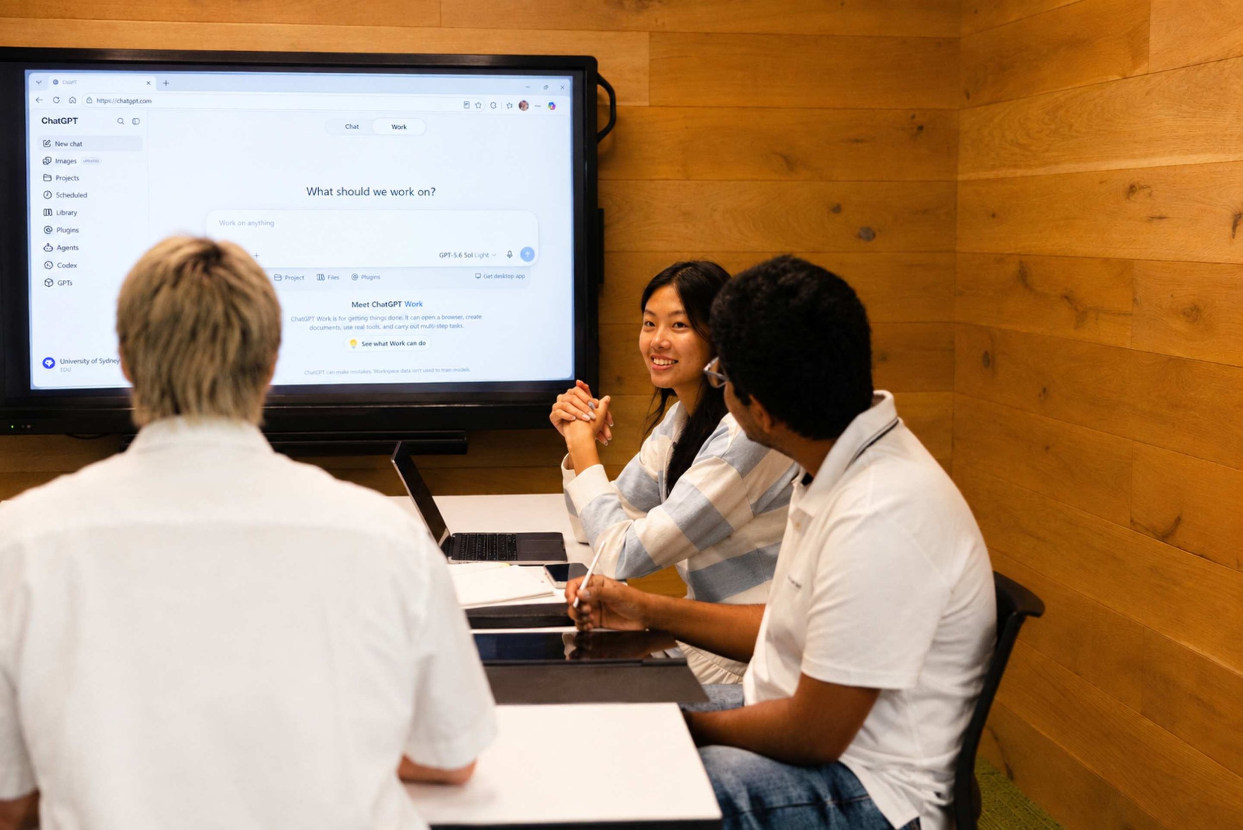 Pictured are three students at the University of Sydney using Chat GPT on a large screen