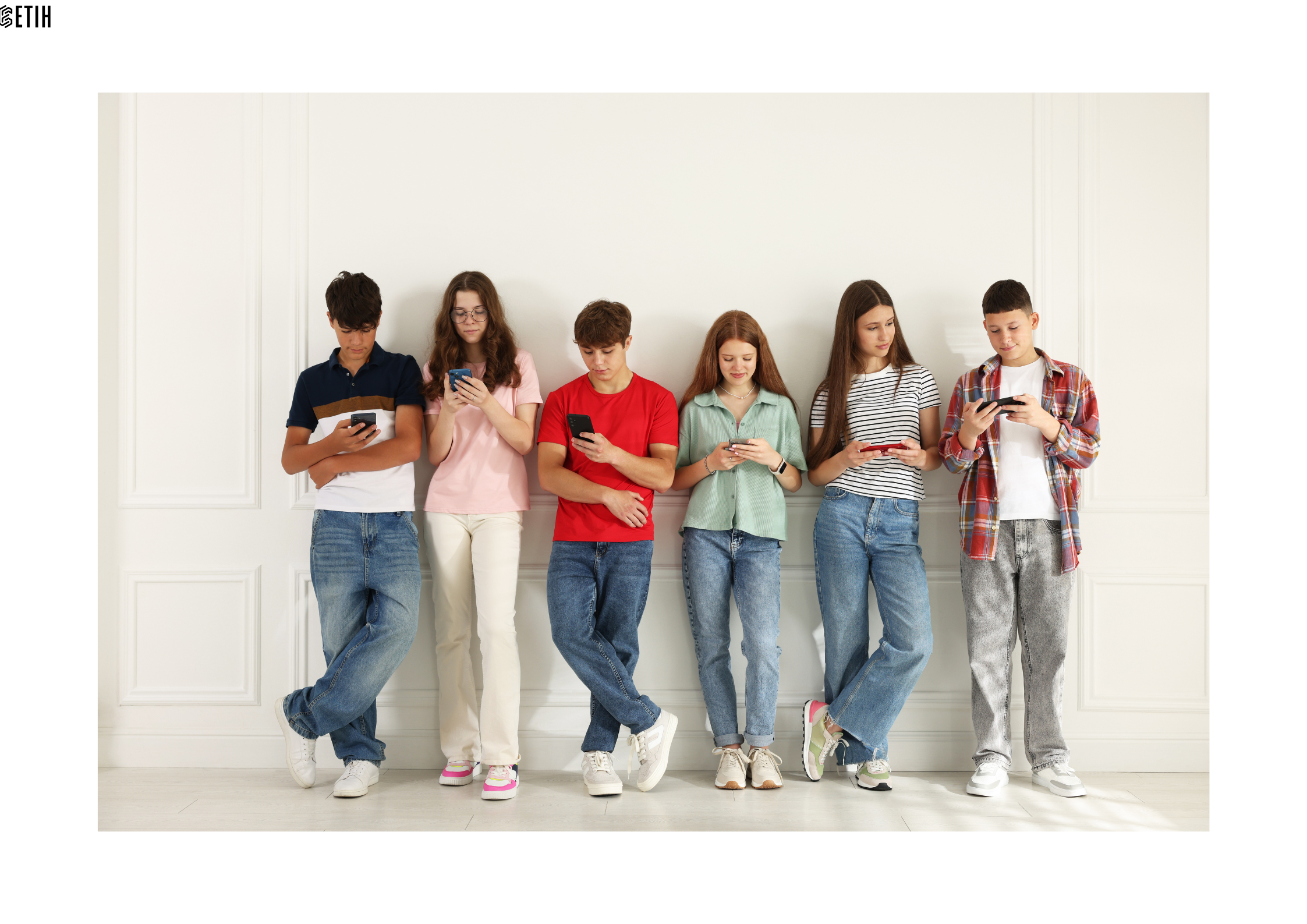 Picture are six young people,alternately three girls and three boys, casually dressed and leaning in a line against a wall, using their mobile phones