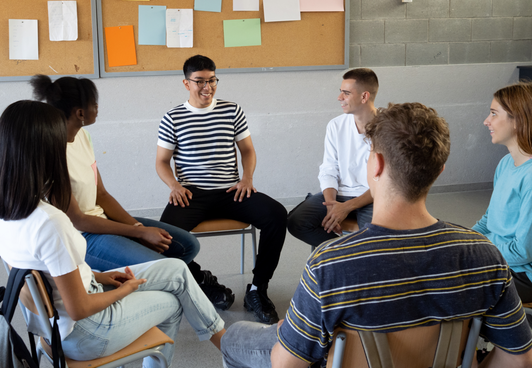 A circle of young people sitting on chairs discussing the harms of online gaming and gambling