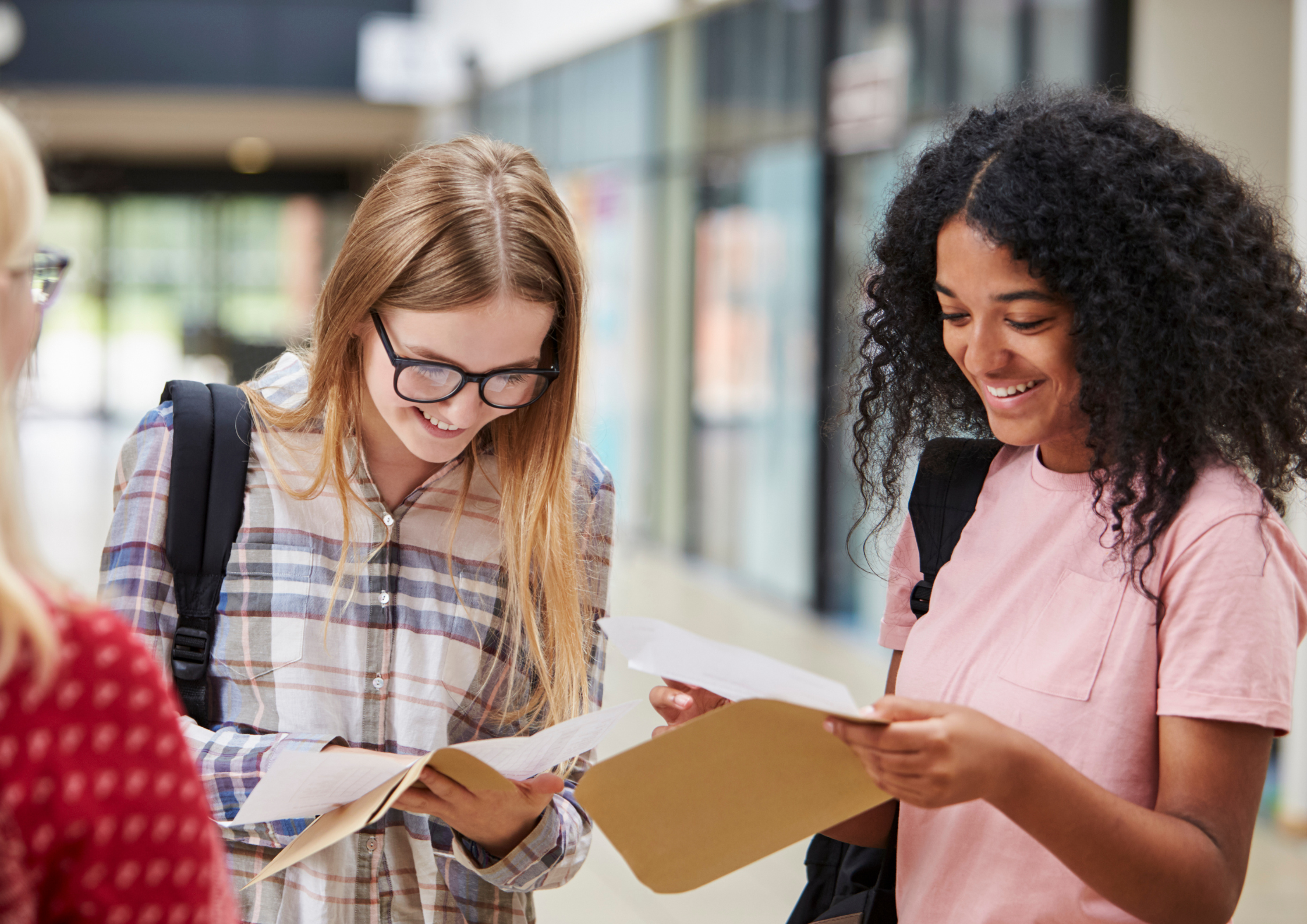 Two students read their exam results at school. The 2026 GCSE data shows an 11.2-point top-grade gap between London and the North East among 16-year-olds in England.