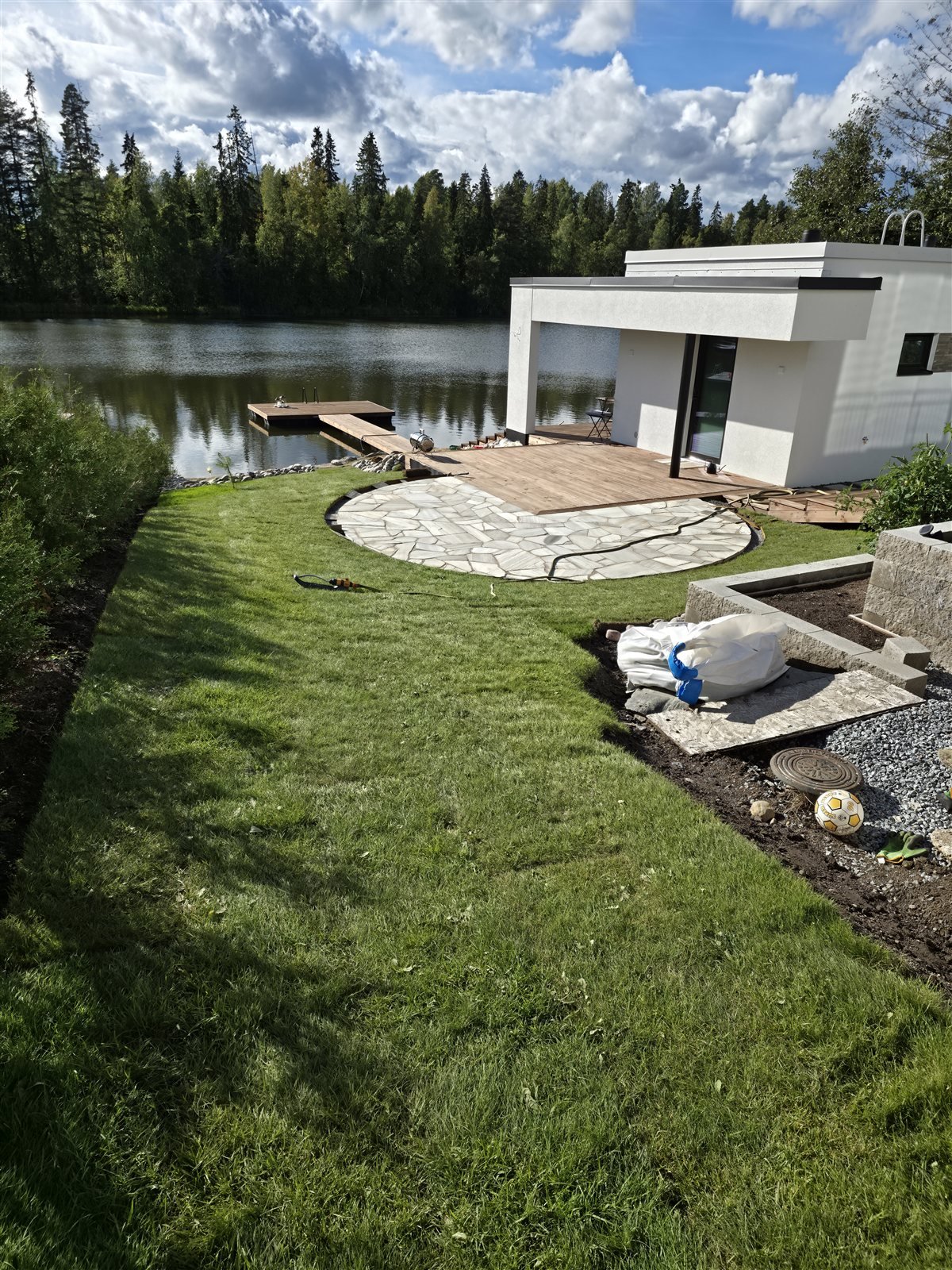 Vaalea pyöreä liuskekiveys ja siirtonurmi puuterassin edessä Nokian Viinikanniemessä
